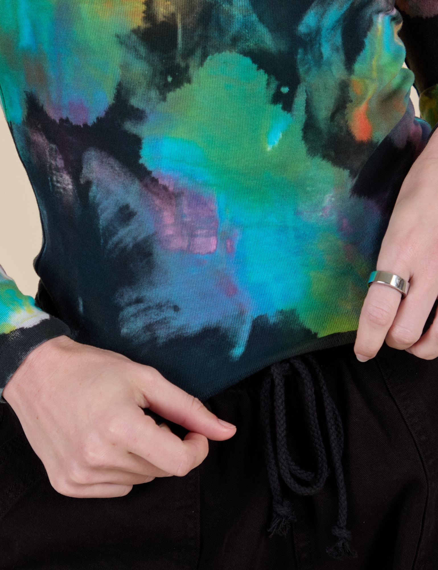 Long Sleeve Baby Tee in Rainbow Magic Waters bottom close up with Alex holding the hem