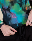 Long Sleeve Baby Tee in Rainbow Magic Waters bottom close up with Alex holding the hem