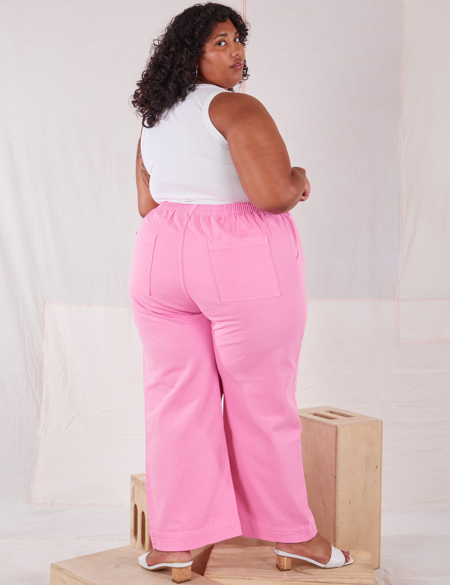 Angled back view of Action Pants in Bubblegum Pink and Tank Top in vintage tee off-white worn by Morgan