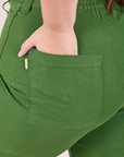 Bell Bottoms in Lawn Green back pocket close up. Marielena has their hand in the pocket.