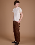 Angled front view of Carpenter Jeans in Fudgesicle Brown and Organic Tee in Vintage Tee Off-White