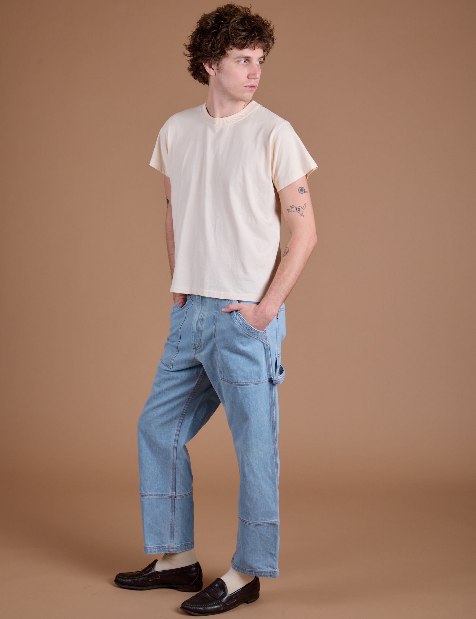 Angled front view of Carpenter Jeans in Light Wash and Organic Vintage Tee in Vintage Tee Off-White on Quinn