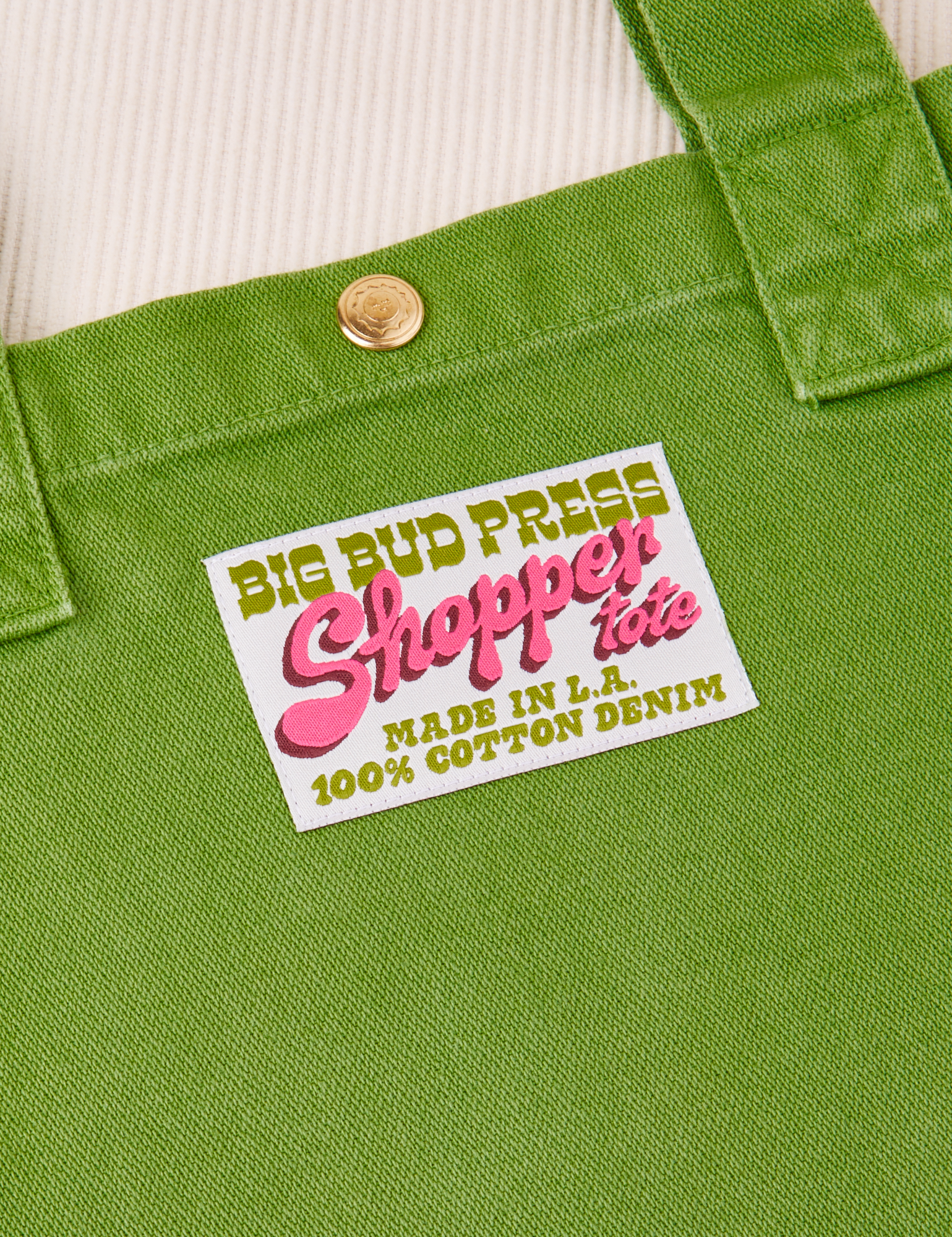 Sun baby brass snap on Shopper Tote Bag in Bright Olive. Bag label with green and pink text that reads &quot;Big Bud Press Shopper Tote, Made in L.A., 100% Cotton Denim on white background