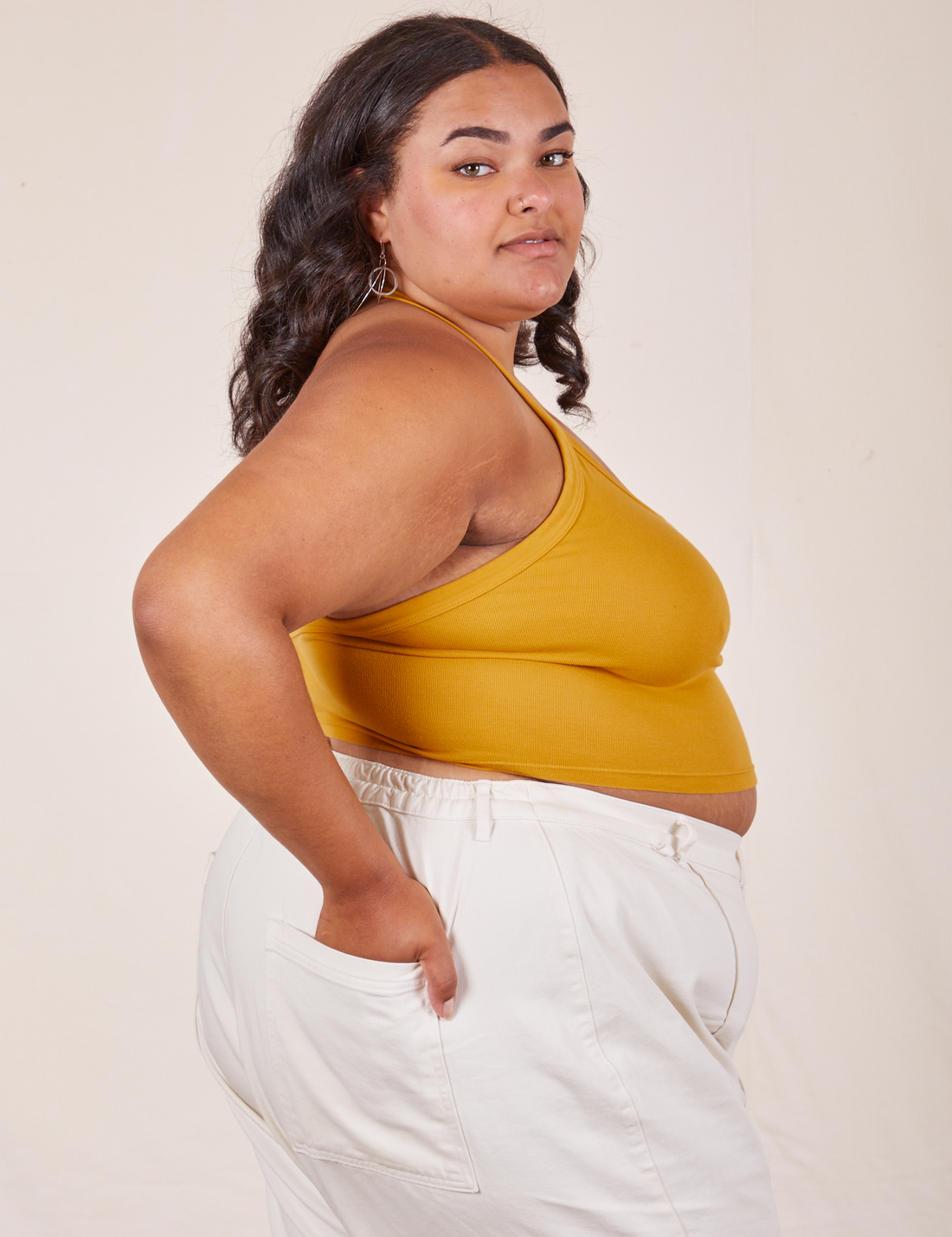 Side view of Halter Top in Mustard Yellow and vintage off-white Western Pants worn by Alicia. She has her left hand in the back pocket of the pants