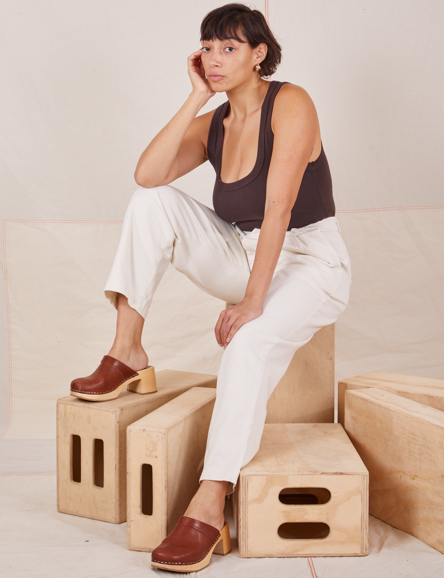 Tiara is sitting on a wooden crate. She is wearing Heavyweight Trousers in Vintage Off-White and espresso brown Cropped Tank Top.