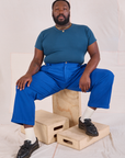 Elijah is wearing Mid-Rise Pleated Trousers in Royal Blue and lagoon Baby Tee