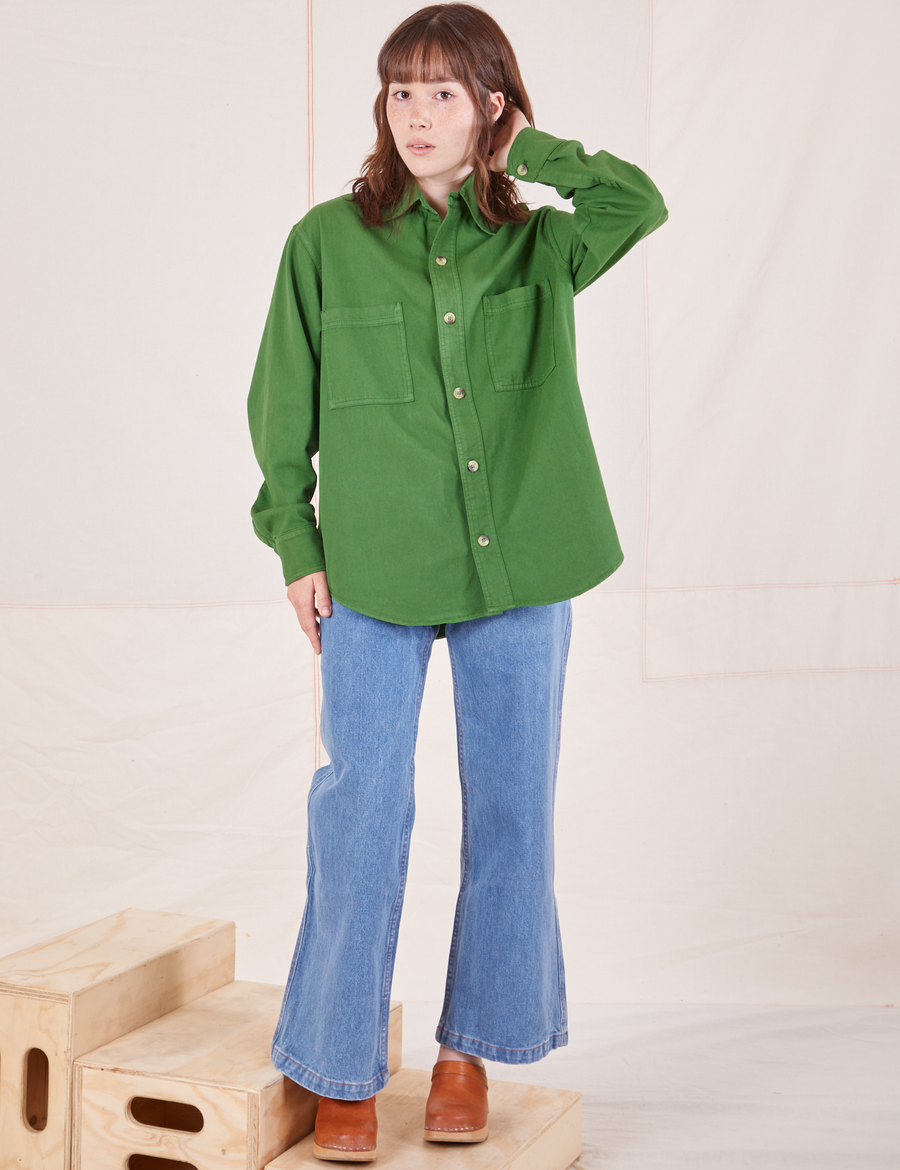 Hana is wearing a buttoned up Oversize Overshirt in Lawn Green paired with light wash Sailor Jeans