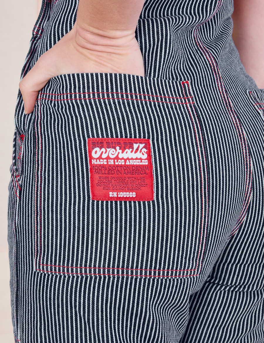 Back pocket close up of Railroad Stripe Denim Original Overalls. Red Big Bud Press Overall label. Alex has her hand in the back pocket.