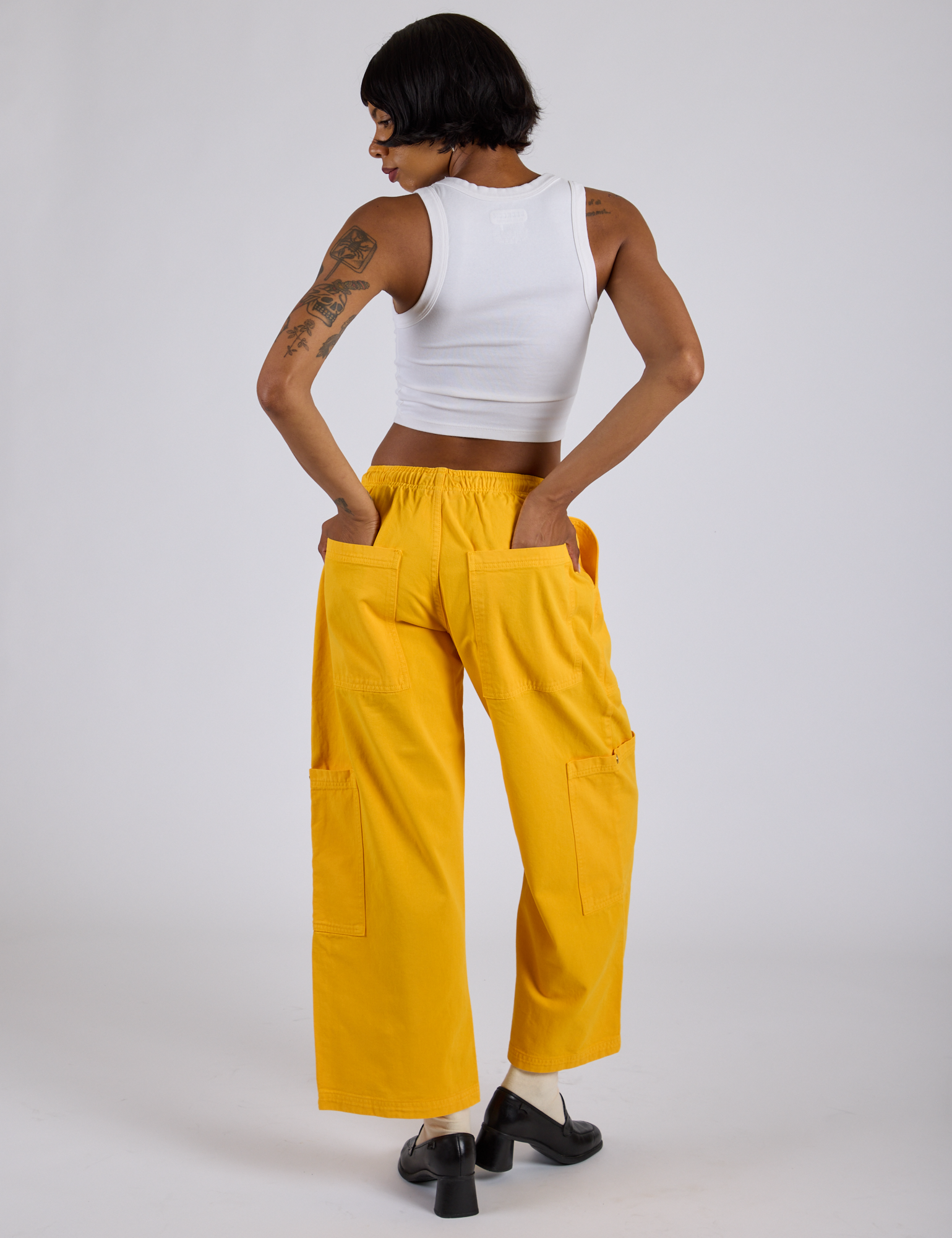 Back view of Drop Pocket Cargo Pants in Sunshine Yellow and Cropped Tank in Vintage Tee White on Kira