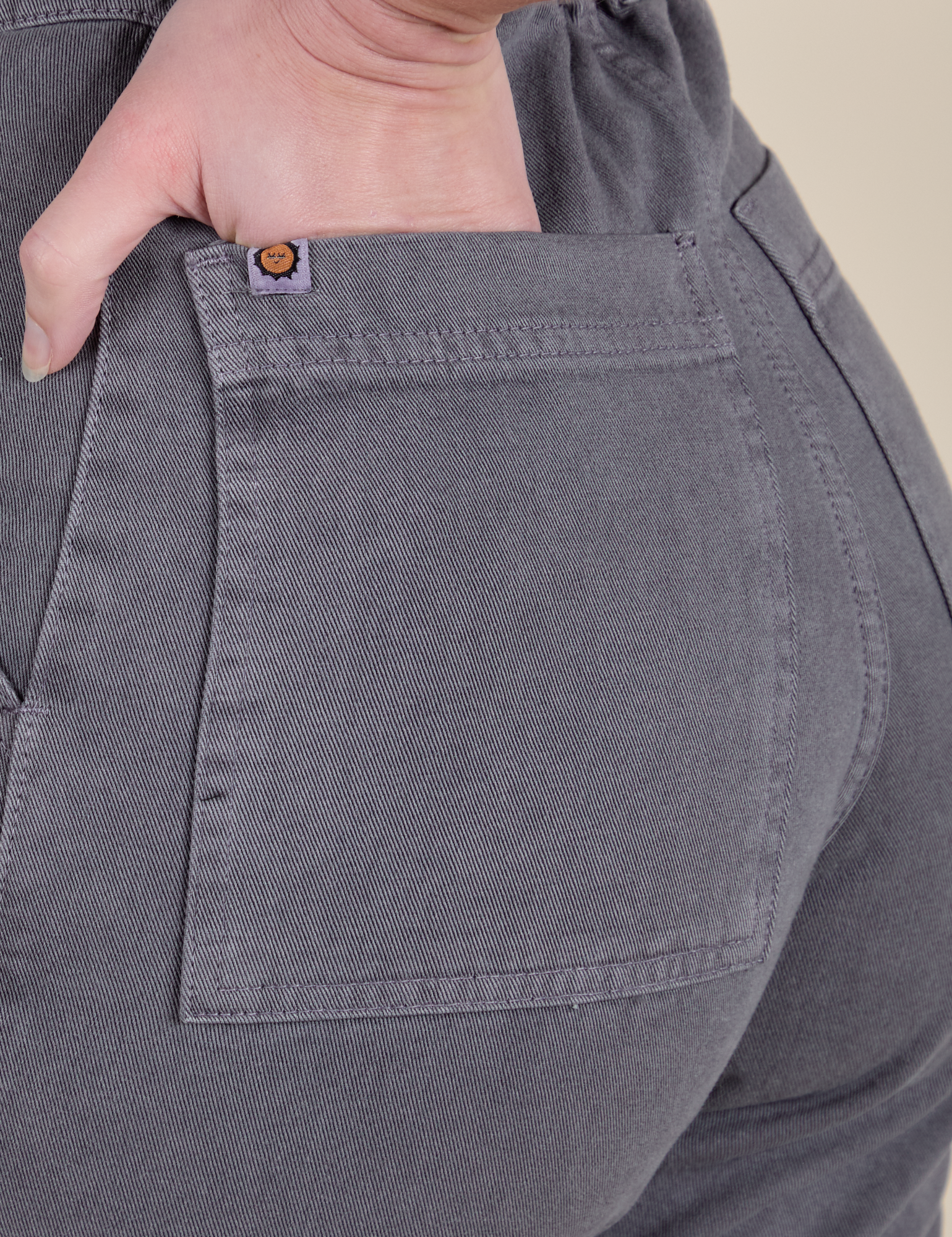Close up of Alex's hand in the back pocket of Short Sleeve Jumpsuit in Washed Grey