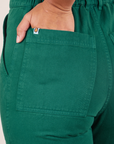 Back pocket close up of Short Sleeve Jumpsuit in Hunter Green. Gabi has her hand in the pocket.