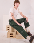 Quinn is sitting in his Carpenter Jeans in Swamp Green