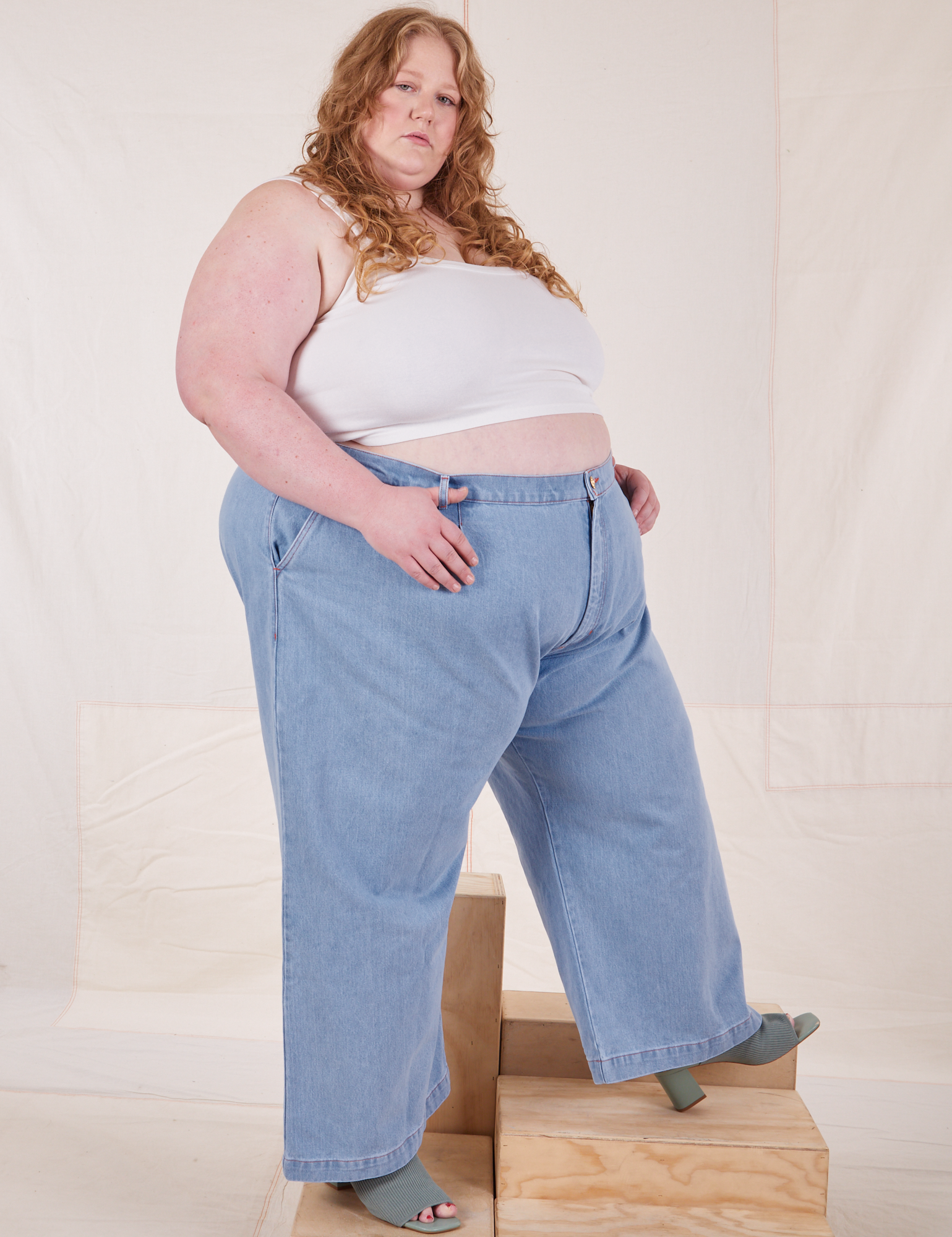Angled view of Indigo Wide Leg Trousers in Light Wash and vintage off-white Cami on Catie