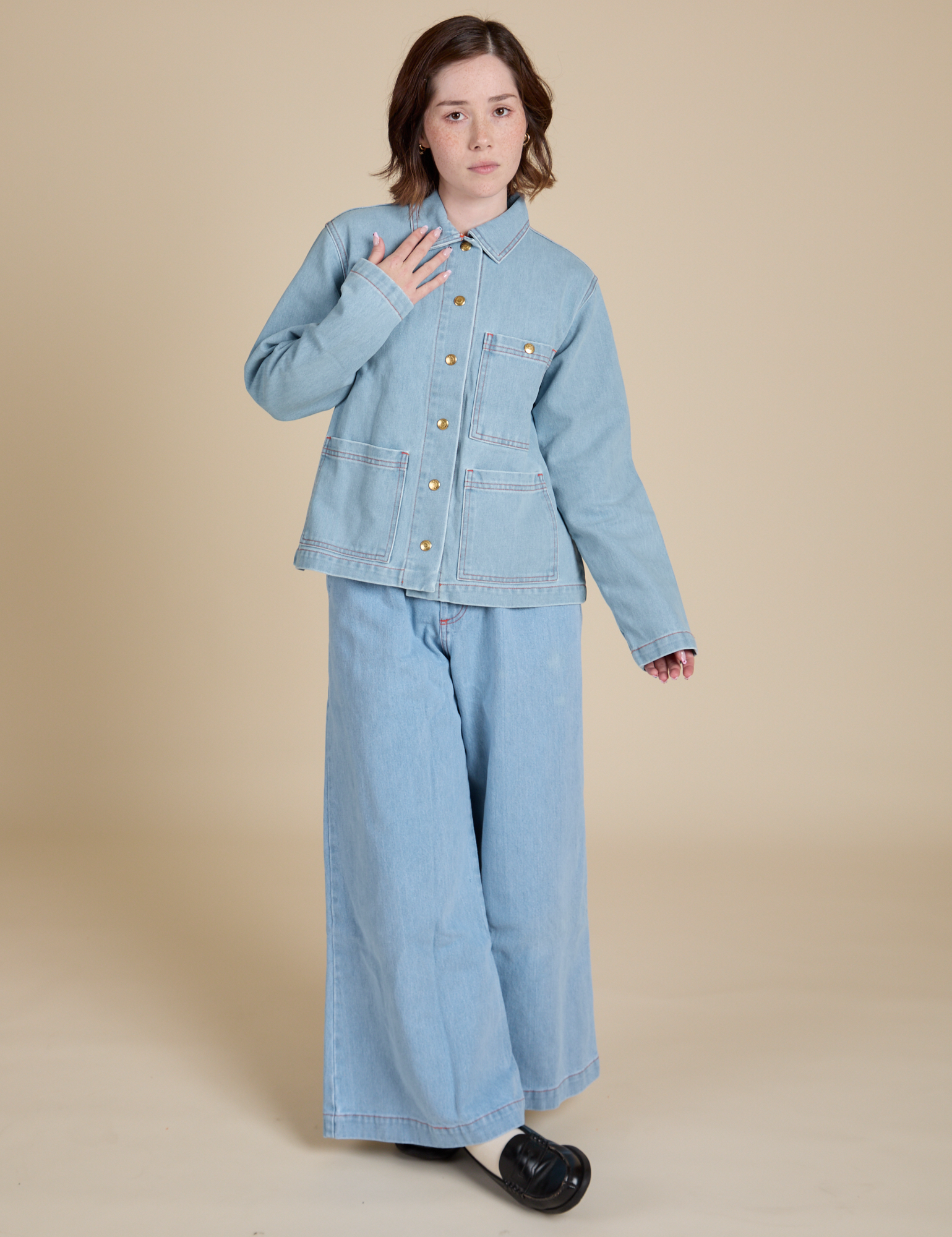 Hana is wearing a buttoned up Indigo Denim Work Jacket in Light Wash paired with light wash Indigo Wide Leg Trousers