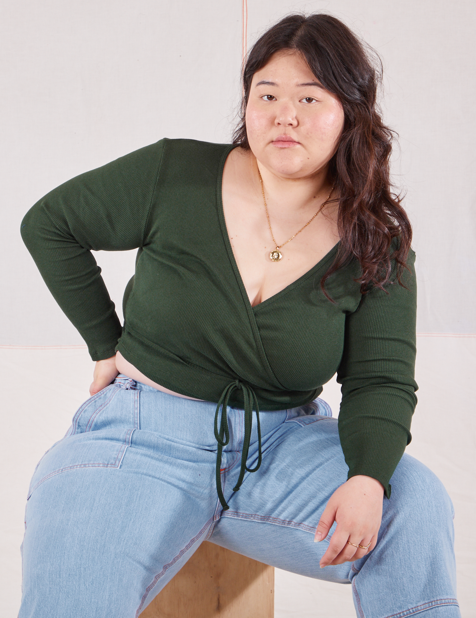 Ashley is wearing Wrap Top in Swamp Green and light wash Carpenter Jeans