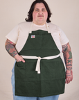 Sam is wearing Full Denim Apron in Swamp Green