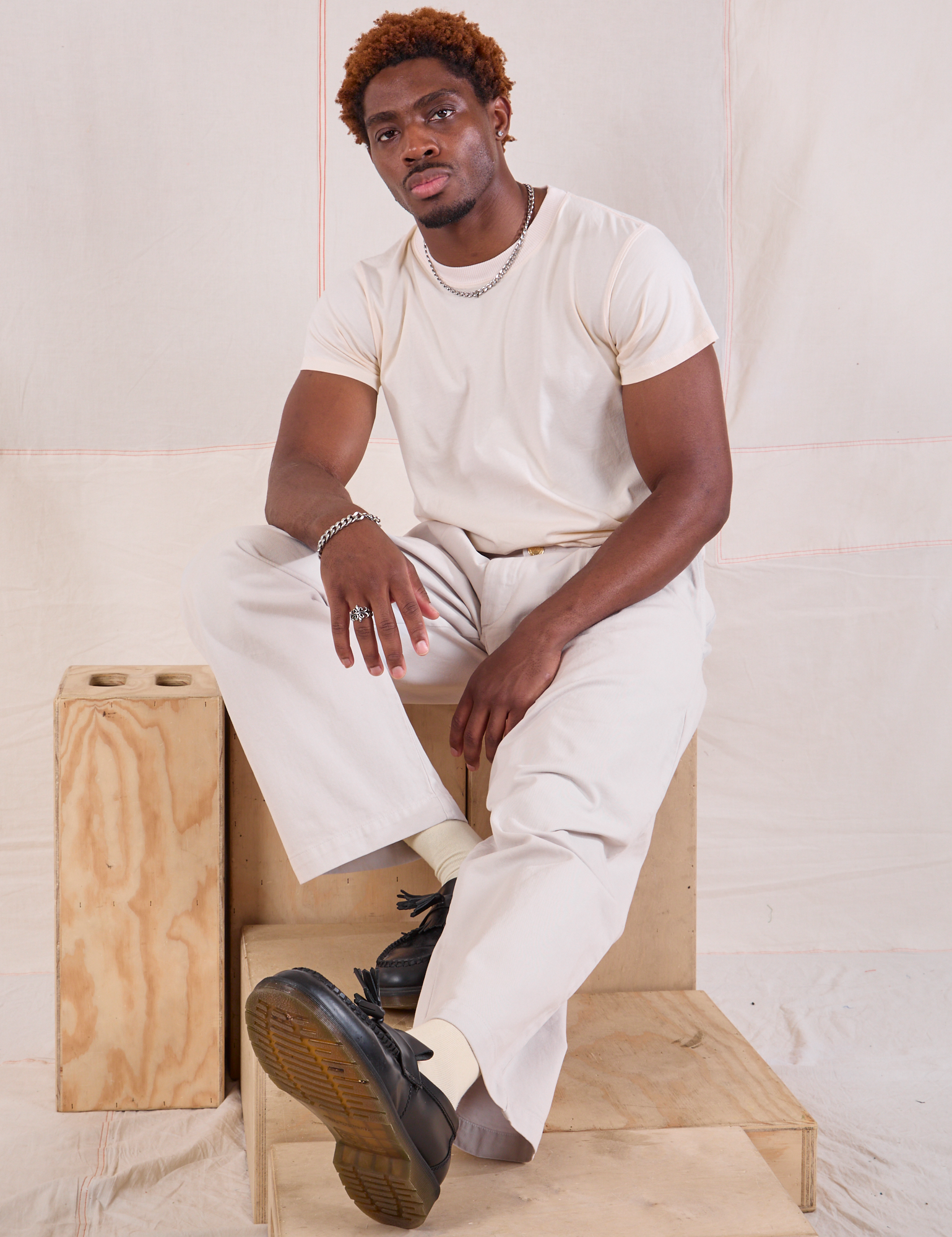 Issac is wearing Mid-Rise Pleated Trousers in Stone White and Organic Vintage Tee in vintage tee off-white