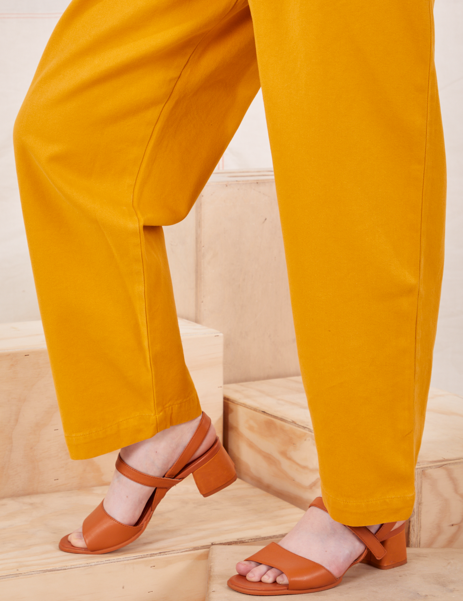 Side view pant leg close up of Organic Trousers in Mustard Yellow worn by Hana
