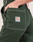 Original Overalls in Swamp Green back pocket close up. Alex has her hand in the pocket.