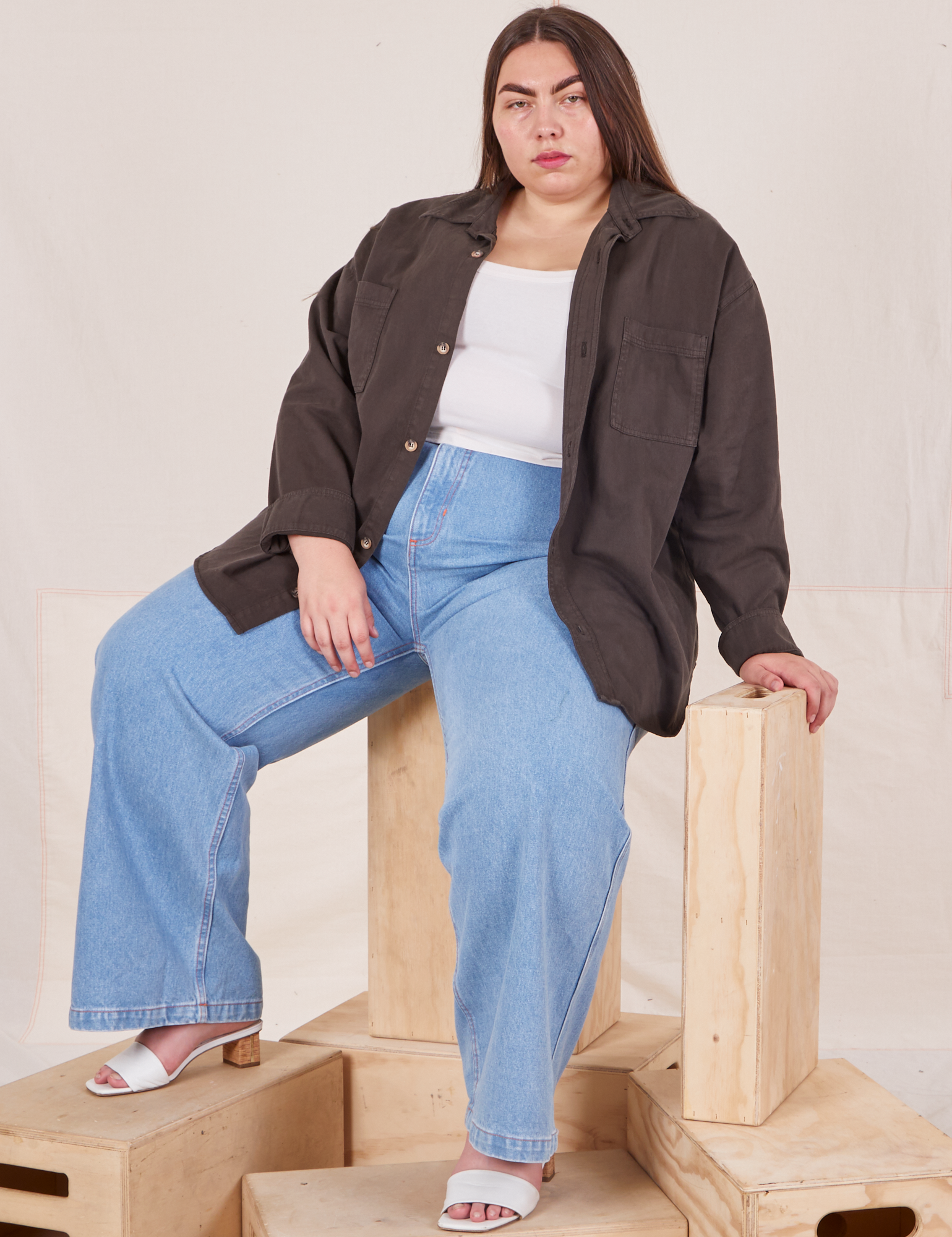 Marielena is wearing Oversize Overshirt in Espresso Brown, vintage off-white Cropped Tank Top, and light wash Sailor Jeans