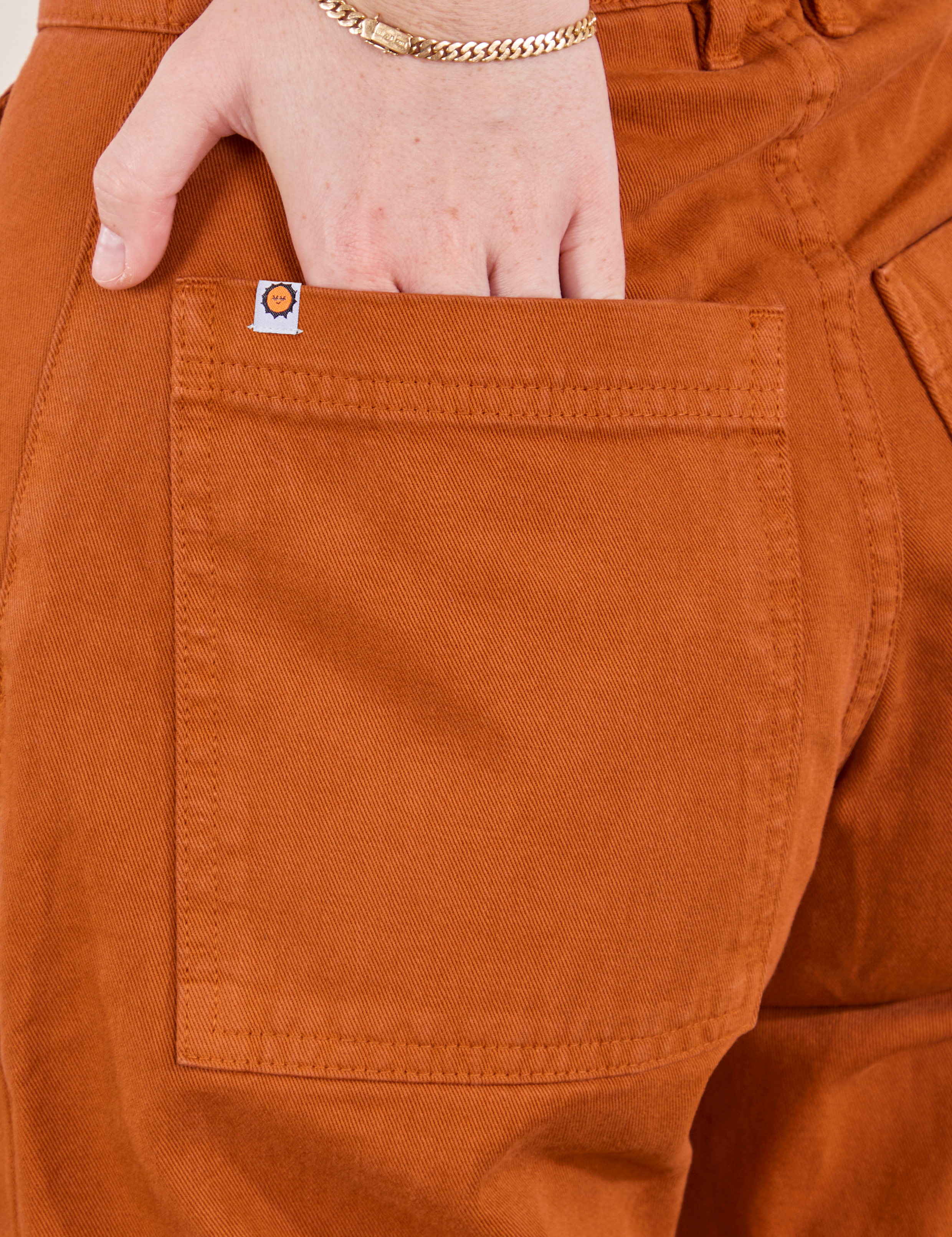 Petite Pencil Pants in Burnt Terracotta back pocket close up. Hana has her hand in the pocket.