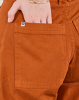 Petite Pencil Pants in Burnt Terracotta back pocket close up. Hana has her hand in the pocket.