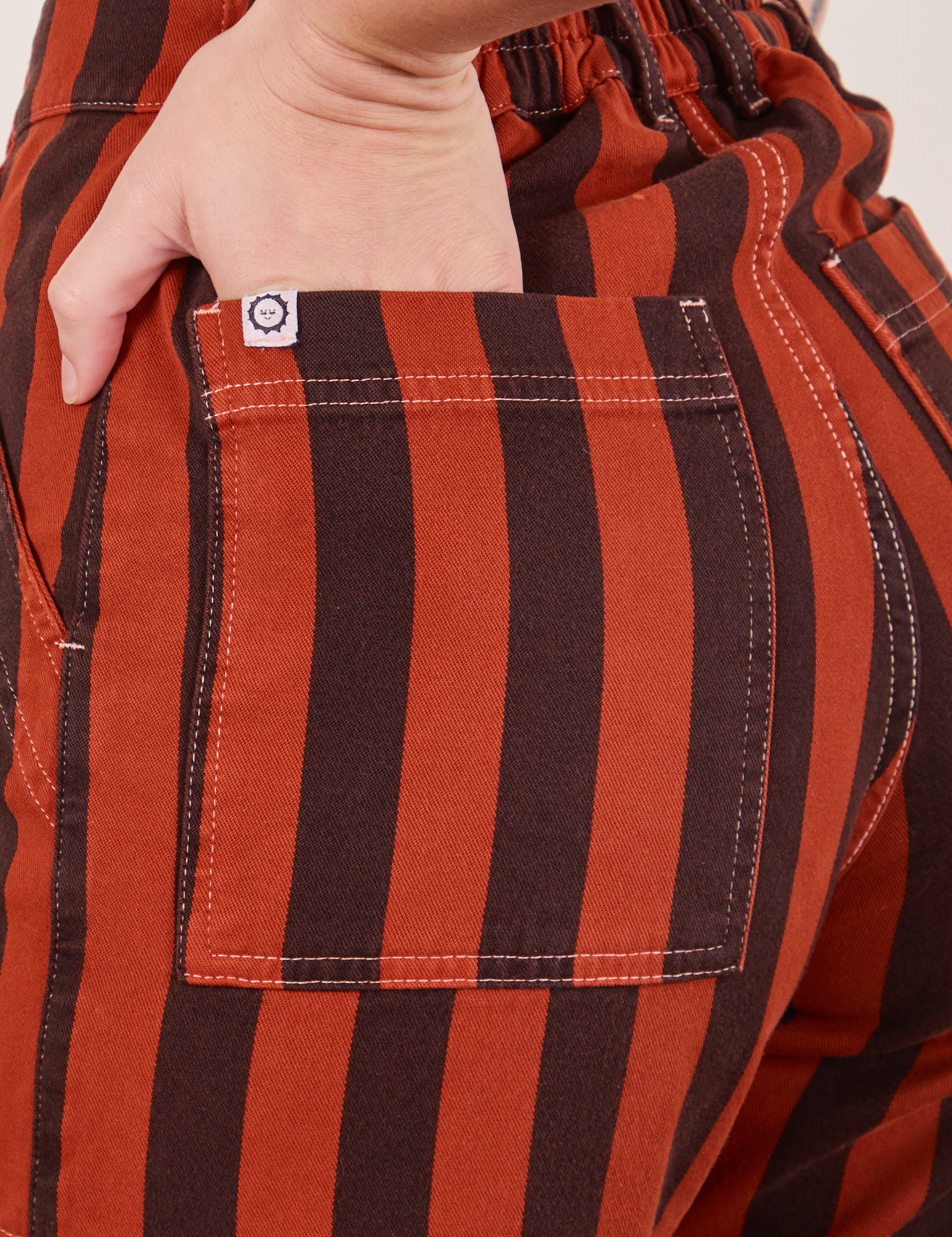 Black Striped Work Pants in Paprika back pocket close up. Alex has her hand in the pocket.