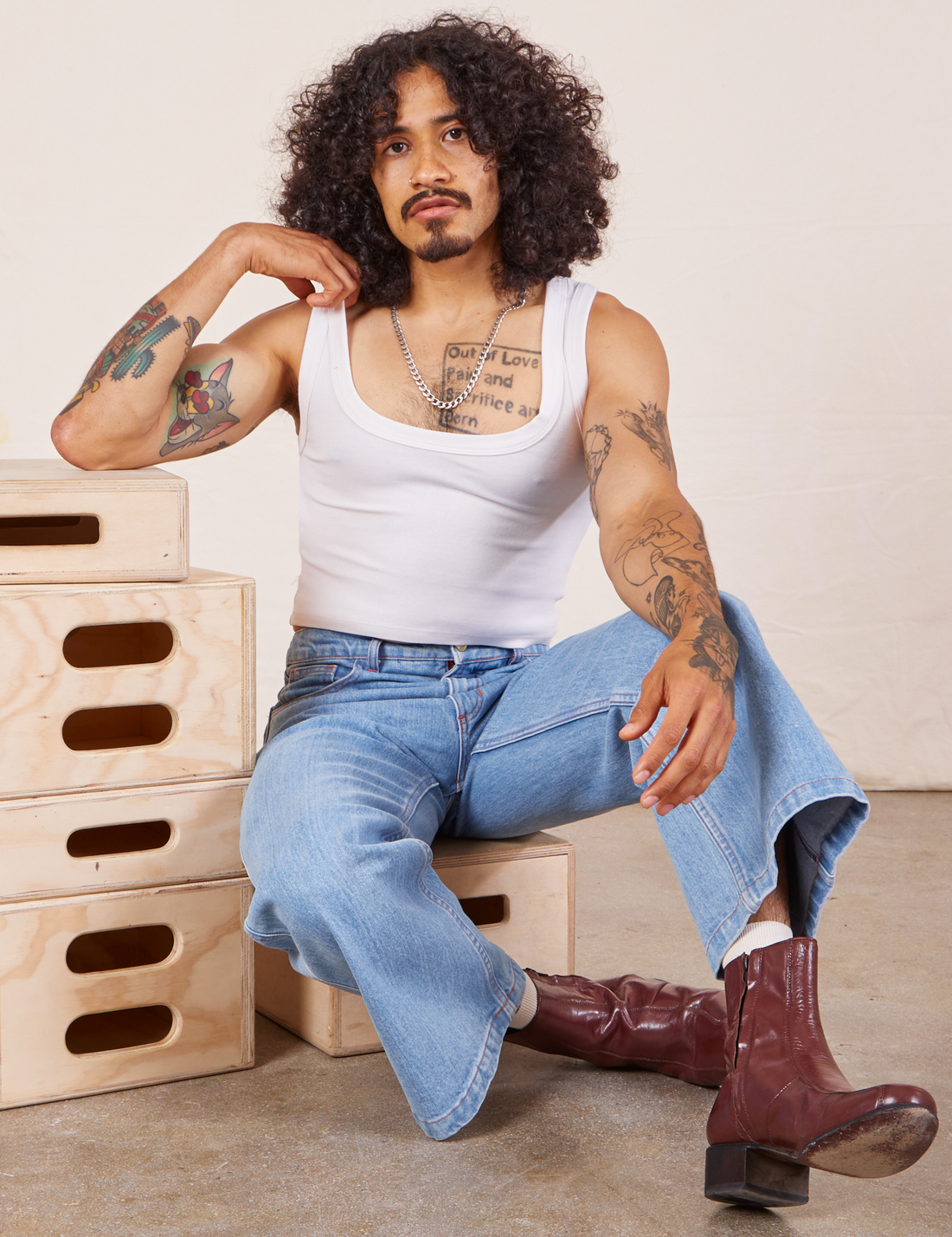Jesse is wearing Cropped Tank Top in Vintage Off-White and sitting on a wooden crate