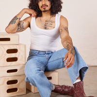 Jesse is wearing Cropped Tank Top in Vintage Off-White and sitting on a wooden crate