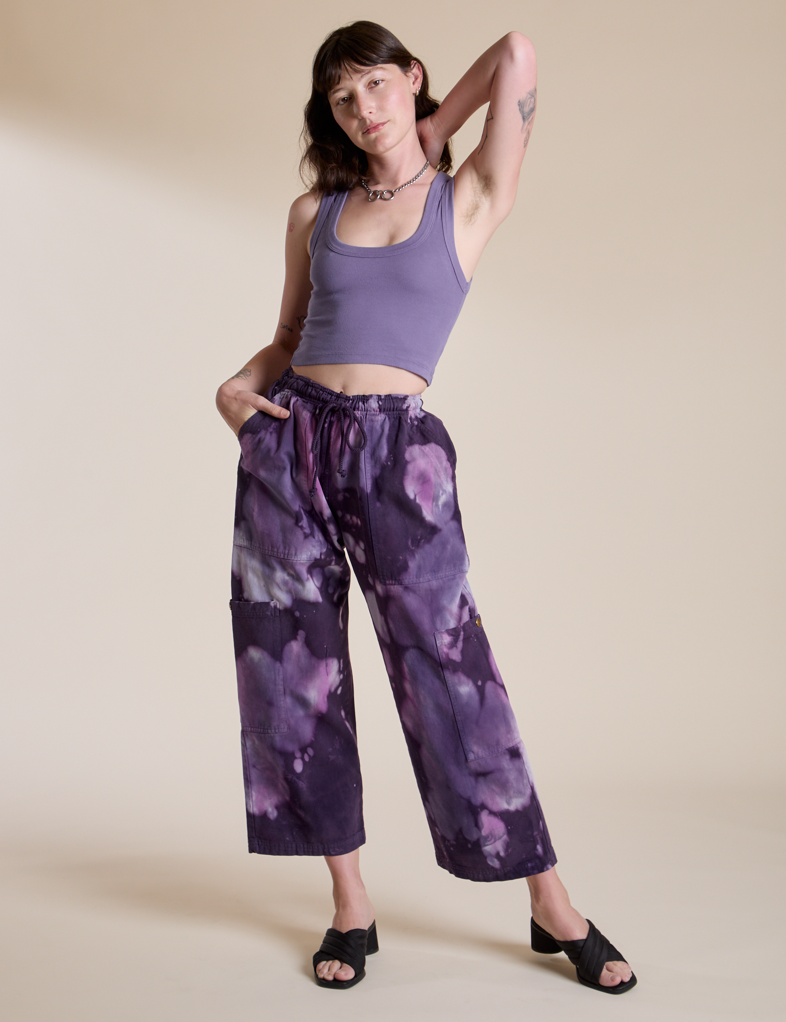 Alex is 5’8” and wearing XXS Magic Waters Drop Pocket Pants in Dark Lavender paired with faded grape Cropped Tank