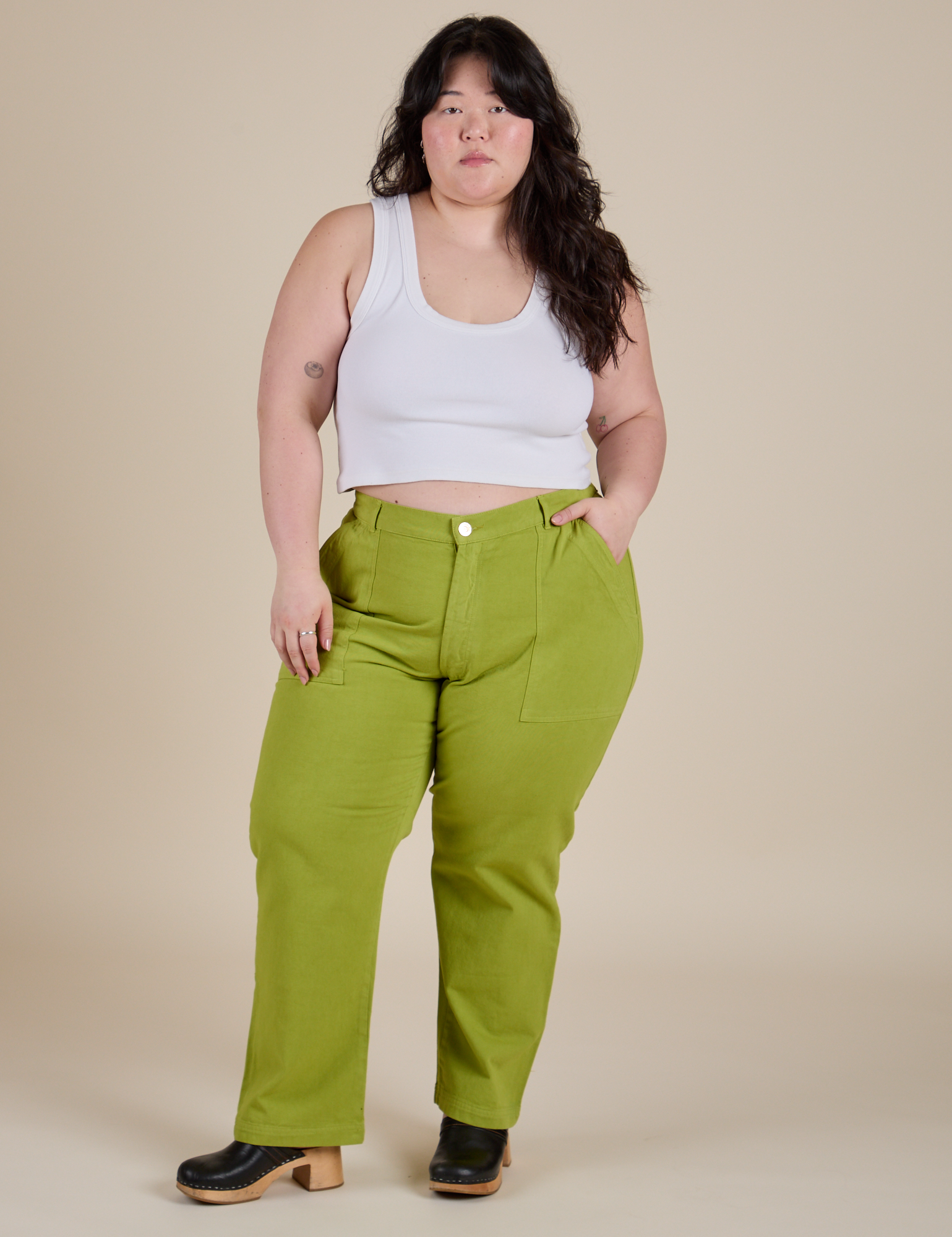 Ashley is 5’7” and wearing 1XL Work Pants in Gross Green paired with vintage tee white Cropped tank