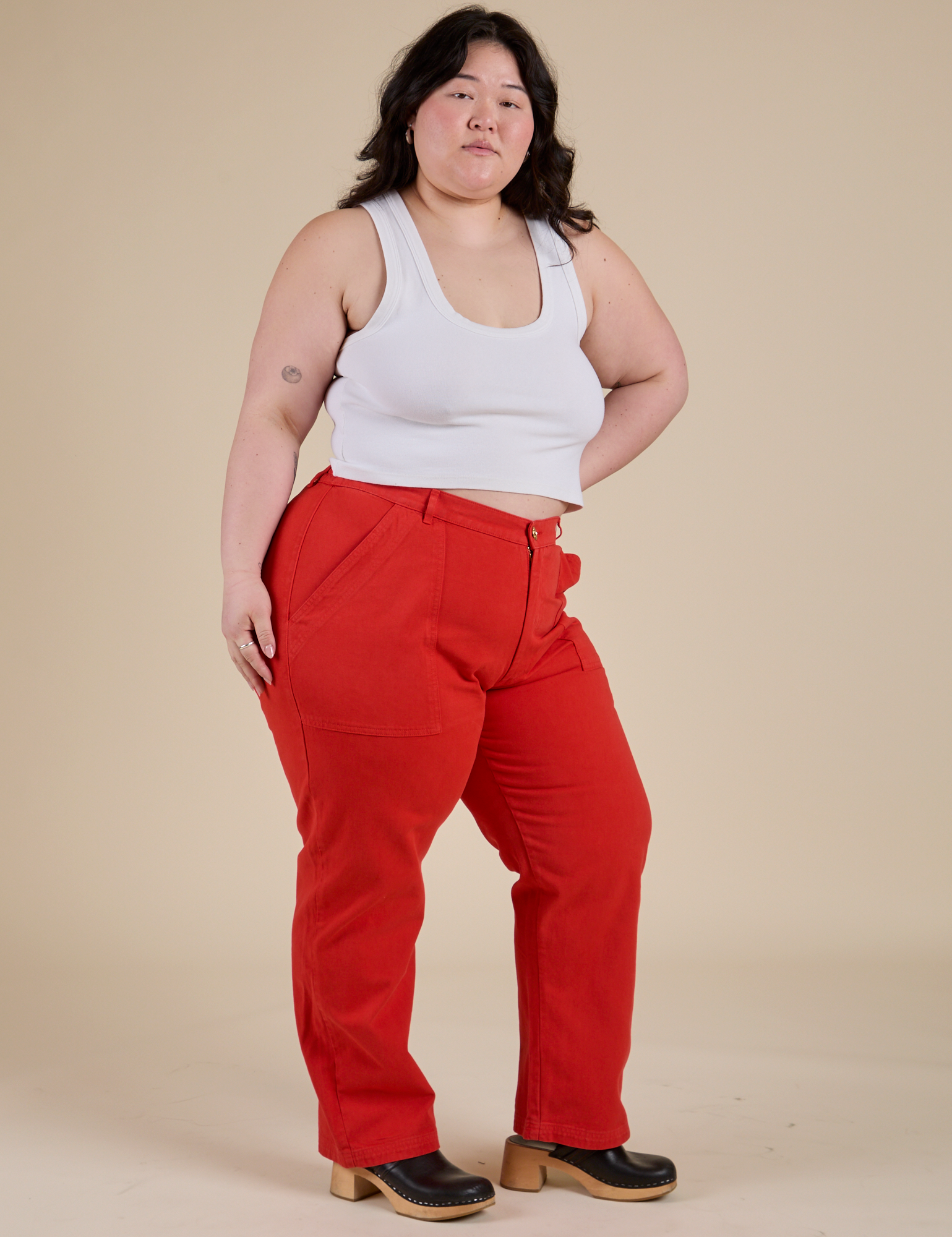 Angled front view of Work Pants in Mustang Red and Cropped Tank in Vintage Tee White on Ashley