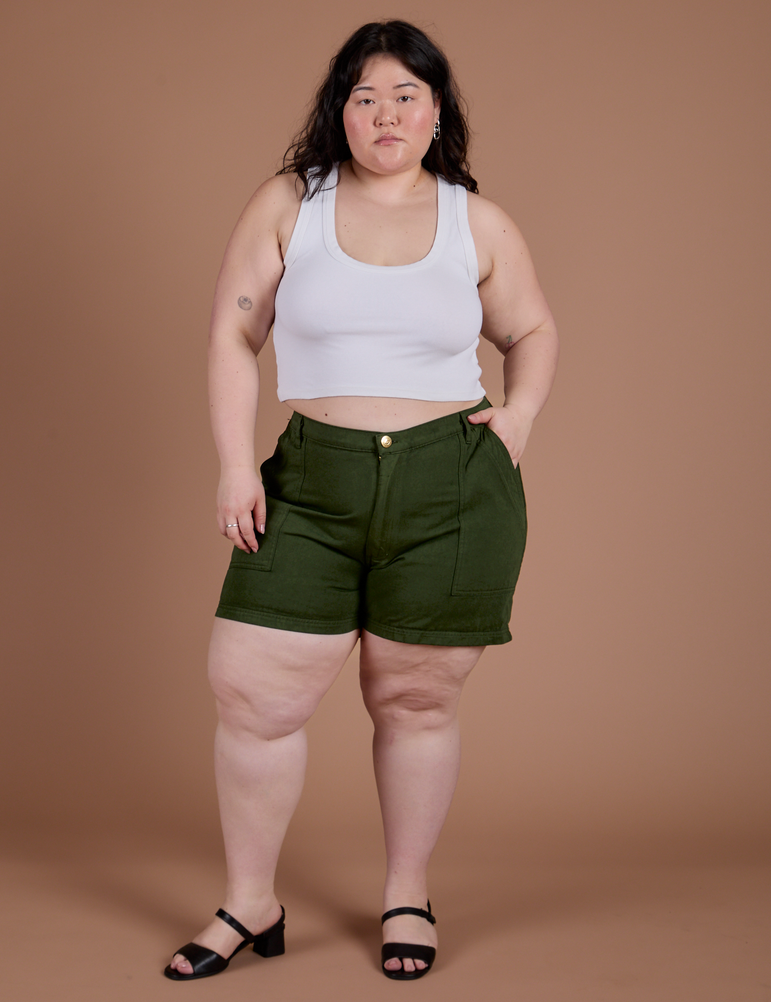 Ashley is 5’7” and wearing 1XL Classic Work Shorts in Evergreen paired with a Cropped Tank in Vintage Tee White