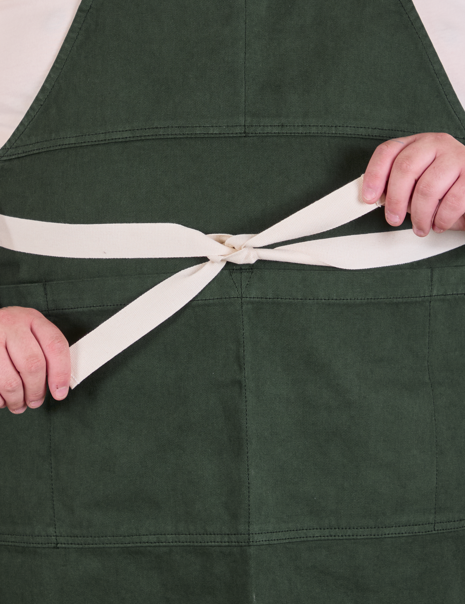 Full Denim Apron in Swamp Green with strap tied around waist in a bow