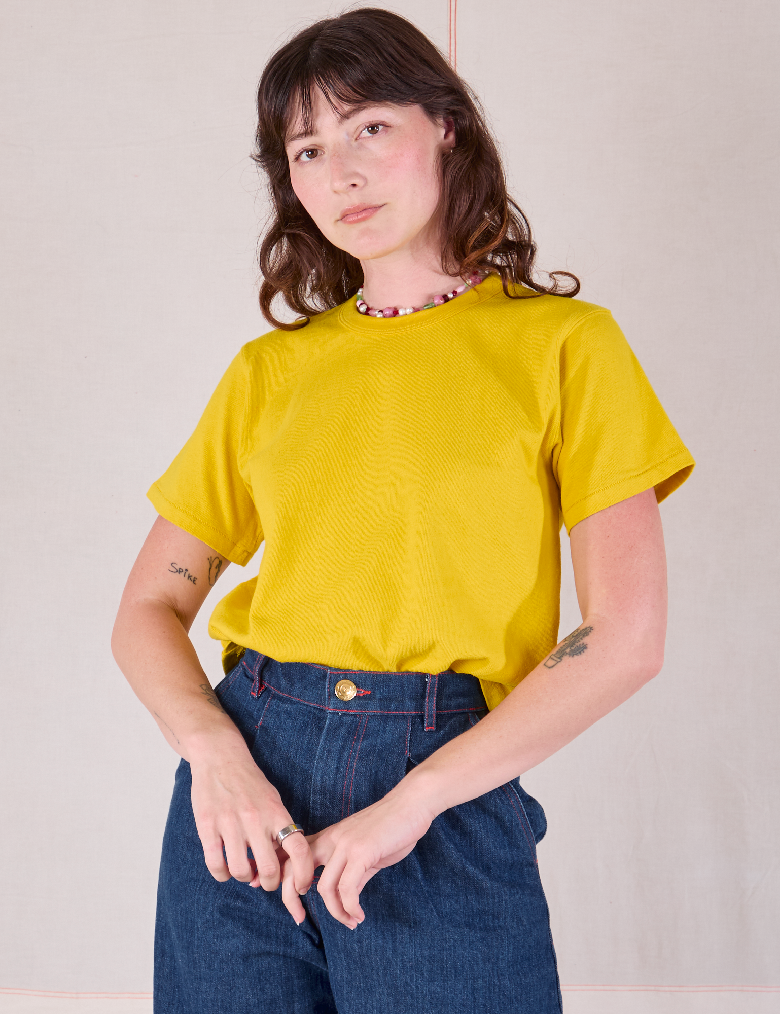 Burly Tee in Golden Yellow tucked into dark wash Denim Wide Leg Trousers on Alex