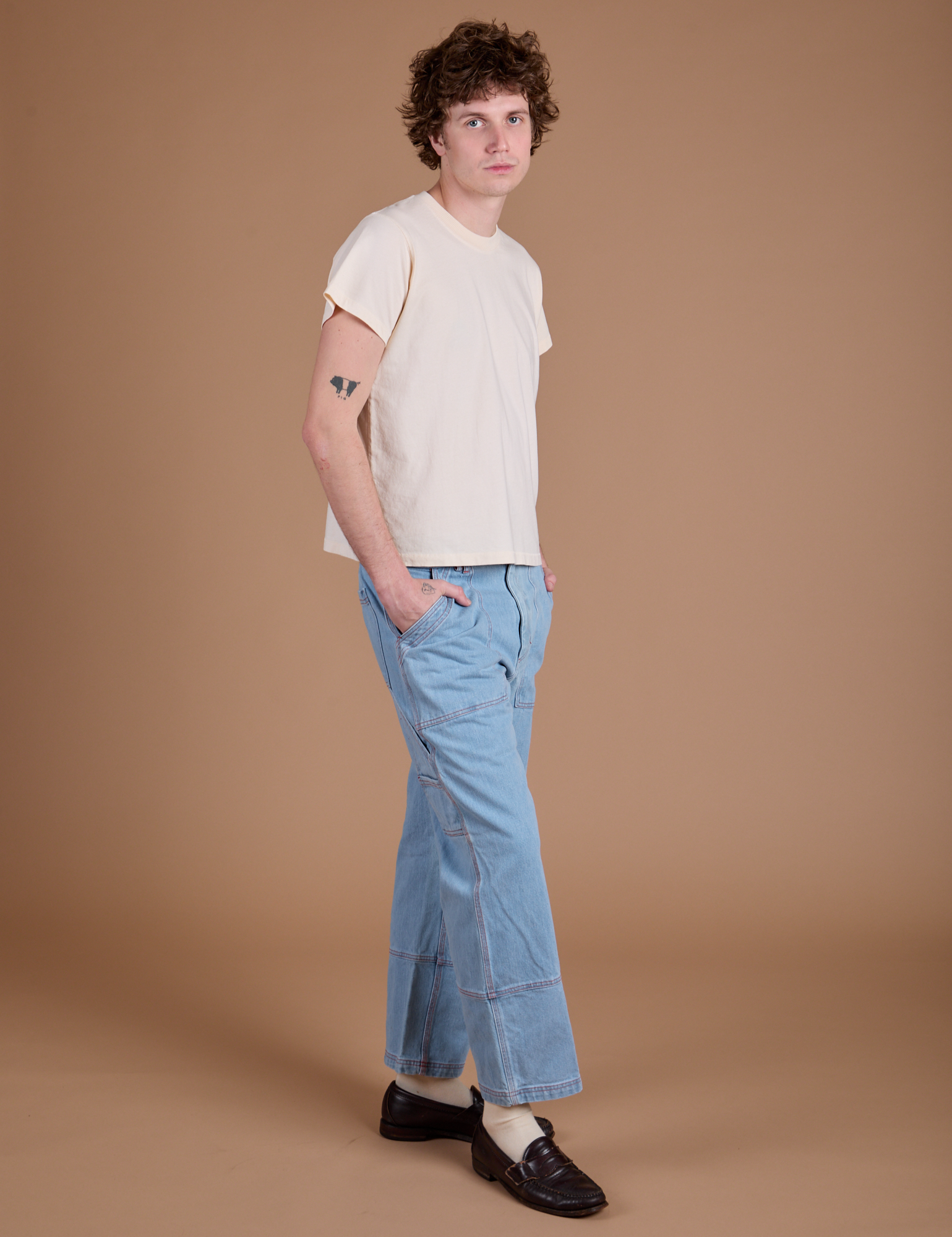 Angled front view of Carpenter Jeans in Light Wash and Organic Vintage Tee in Vintage Tee Off-White on Quinn