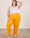 Marielena is 5'8" and wearing 2XL Cropped Rolled Cuff Sweatpants in Mustard Yellow paired with vintage off-white Cropped Tank Top