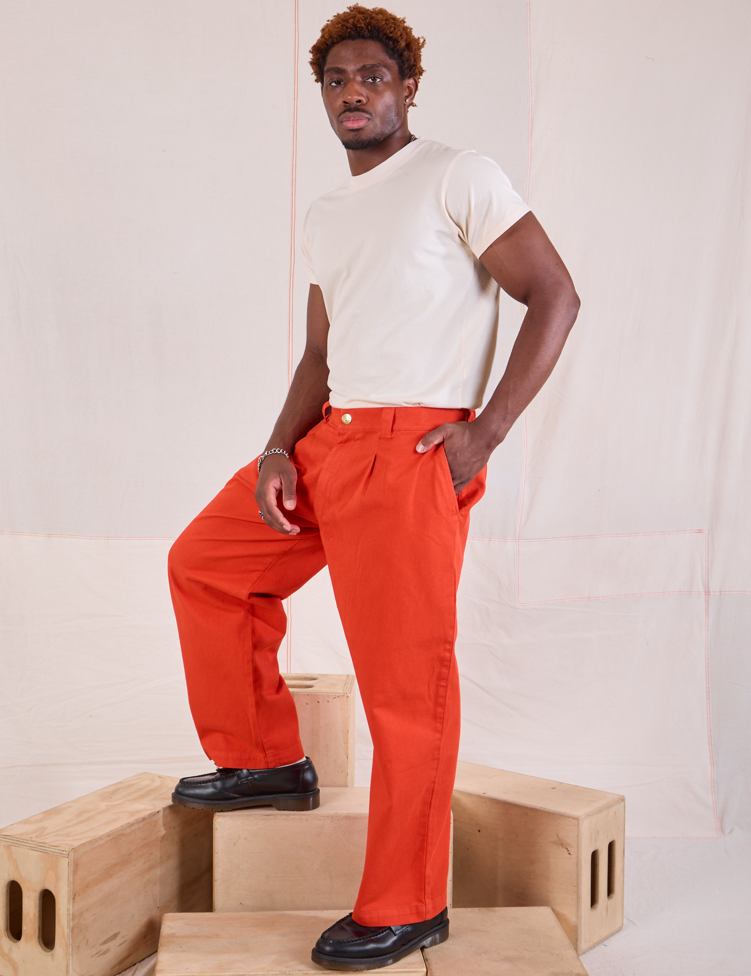 Angled front view of Mid-Rise Pleated Trousers in Chili Red and Organic Vintage Tee in vintage tee off-white