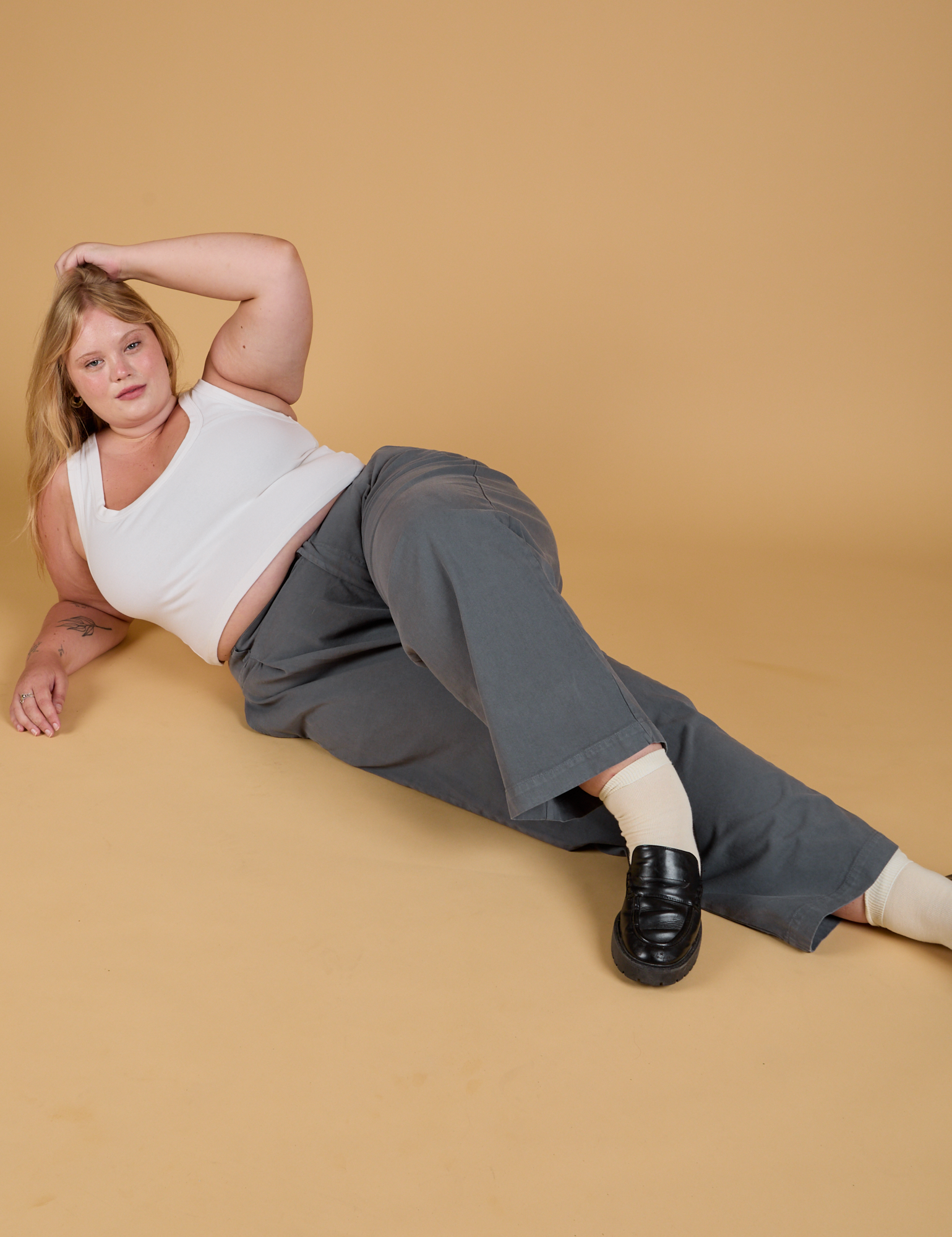 Juliet is laying down on the floor wearing Baggy Mid-Rise Trousers in Slate Grey and vintage tee white Cropped Tank 