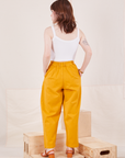 Back view of Organic Trousers in Mustard Yellow and vintage off-white Cami worn by Hana