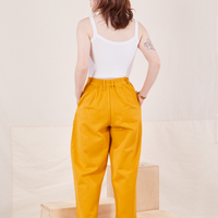 Back view of Organic Trousers in Mustard Yellow and vintage off-white Cami worn by Hana