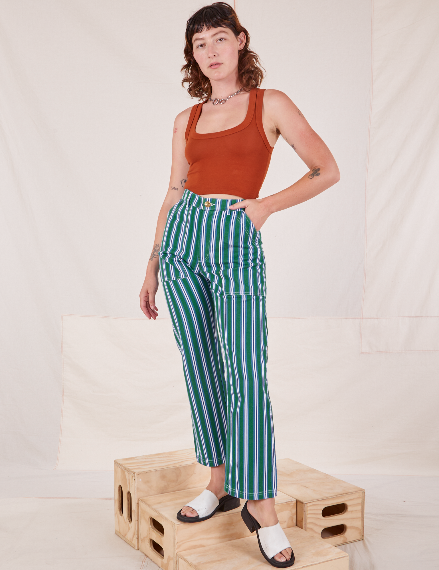 Alex is wearing Stripe Work Pants in Green and burnt terracotta Cropped Tank Top
