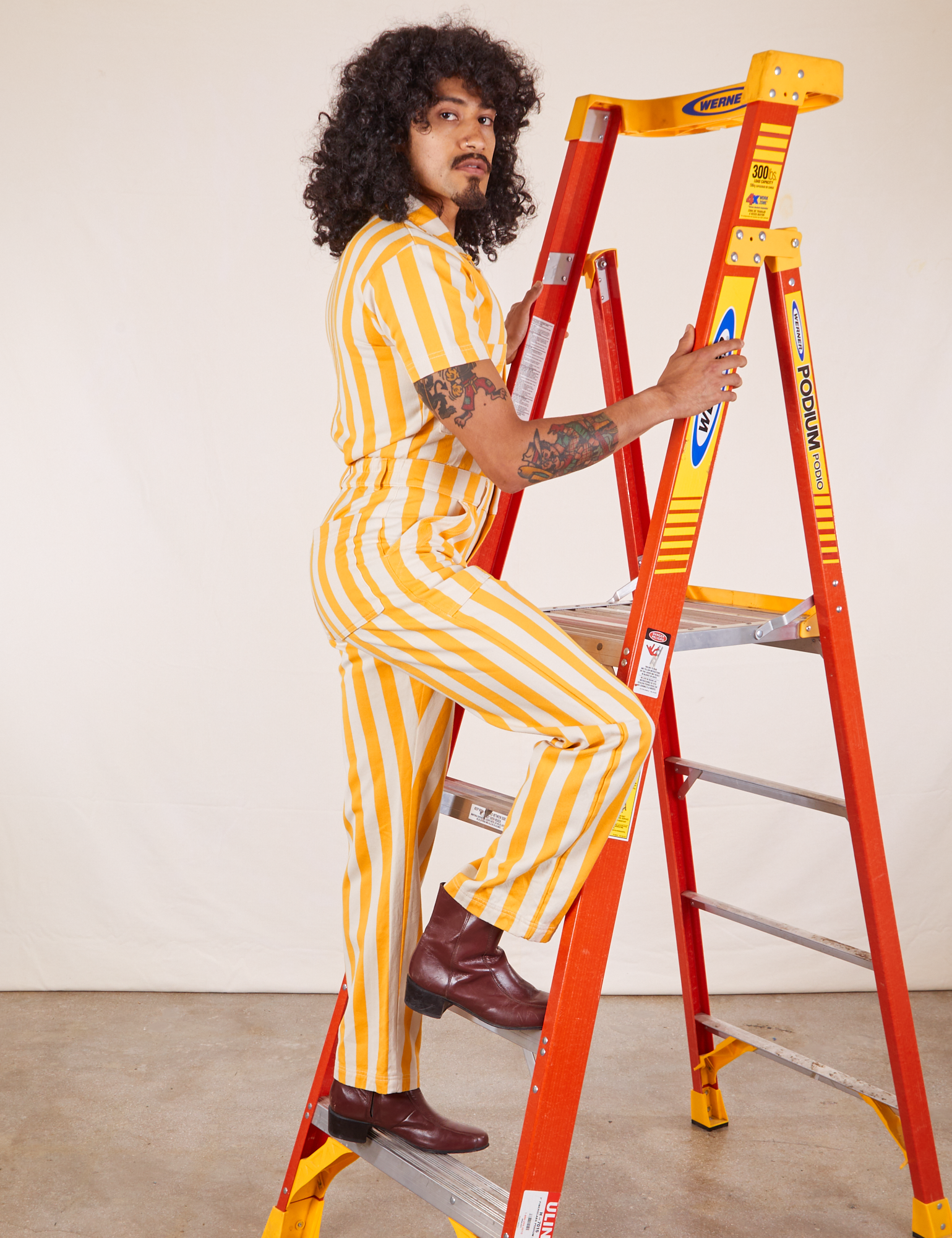 Side view of Lemon Stripe Jumpsuit on Jesse climbing a ladder.
