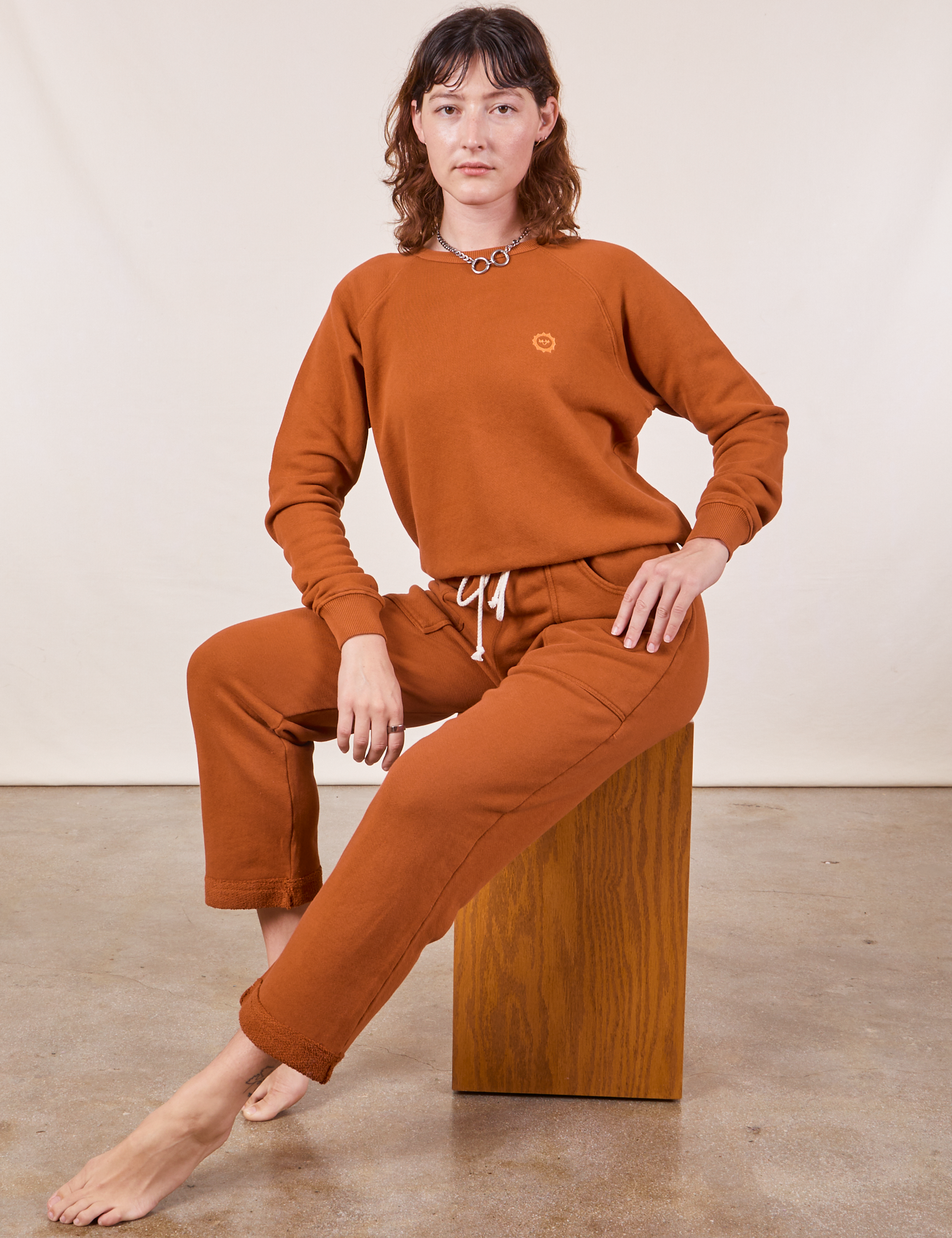Alex is Cropped Rolled Cuff Sweatpants in Burnt Terracotta and matching Heavyweight Crew Sweatshirt