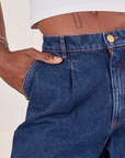 Indigo Wide Leg Trousers in Dark Wash front close up. Jerrod has their hand in the pocket.