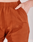 Action Pants in Burnt Terracotta front pocket close up. Alex has her hand in the pocket.