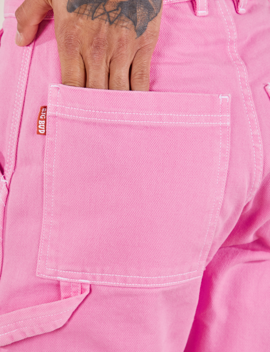 Carpenter Jeans in Bubblegum Pink back pocket close up. Jesse has their hand in the pocket.