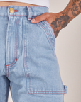 Front close up of Carpenter Jeans in Light Wash. Jesse has their hand in the pocket.