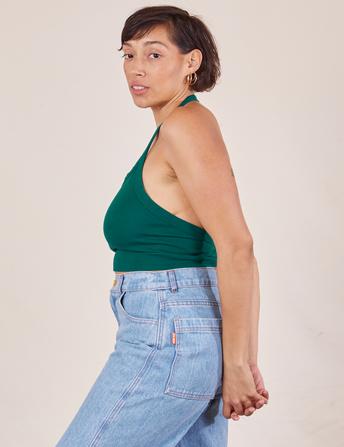 Side view of Halter Top in Hunter Green and light wash Sailor Jeans worn by Tiara