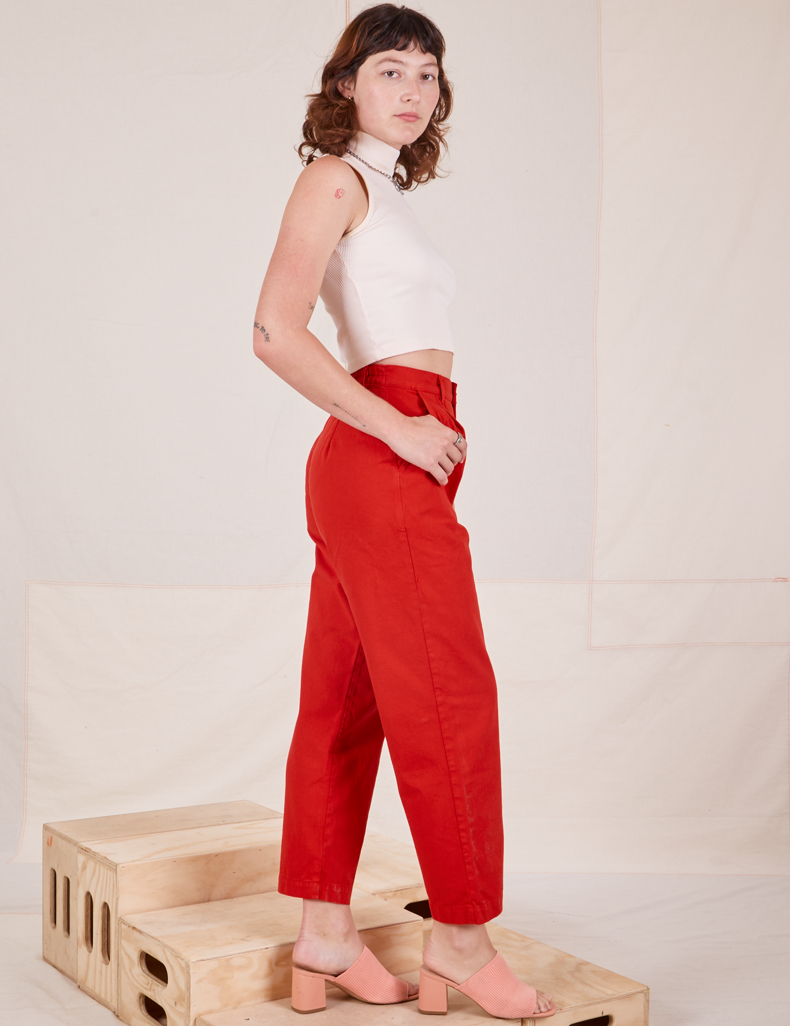 Side view of Heavyweight Trousers in Mustang Red and vintage off-white Sleeveless Turtleneck worn by Alex